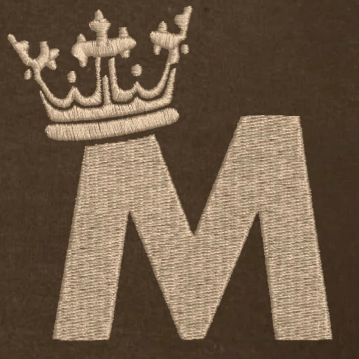 Embroidered letter 'M' with a crown on a dark background