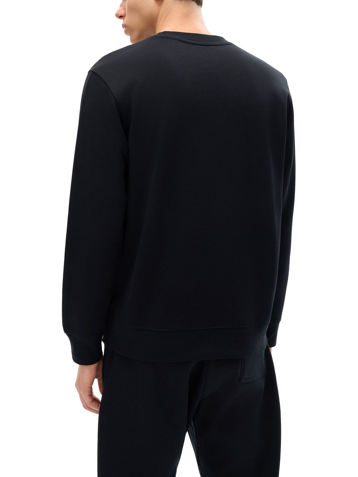 Person wearing a black sweatshirt and pants on a white background